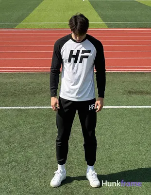 He wears white long-sleeve athletic shirt with black raglan sleeves and bold 'HF' lettering across c