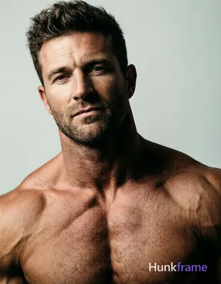 A muscular adult man with light to medium skin, dark brown short textured hair styled upward, and sh