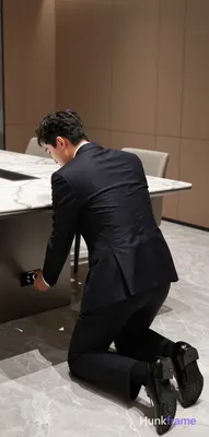 Asian man kneeling beside a large marble conference table in a modern high-end o