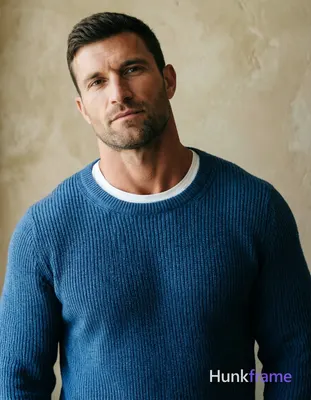 A handsome masculine man standing straight with head slightly tilted forward, we