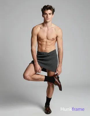 A handsome white man with light skin and dark brown short hair styled upward stands centered in a fu