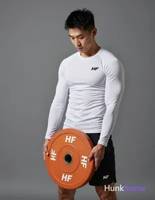 Asian man with light-medium skin and short black textured hair stands in a gym, holding an orange 10