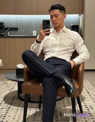 Confident adult man in tasteful suggestive framing, seated on brown leather chai