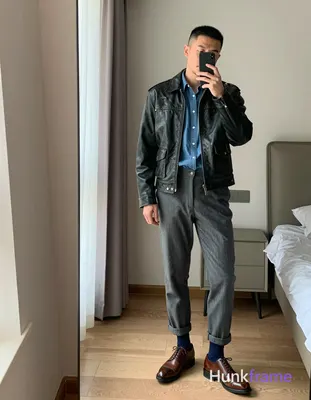 Asian man with short black buzz cut and light stubble stands casually in a modern apartment bedroom,