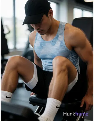 Asian man with light-medium skin seated on gym leg press in vertical portrait, legs spread wide V-sh
