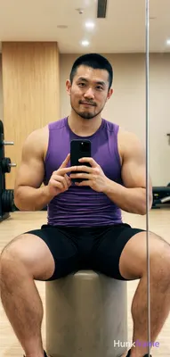 Asian man with short black buzz cut and light stubble sits centered in a gym mirror reflection on a 
