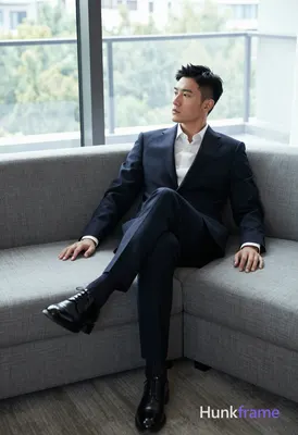 A handsome an anonymous figure man with short black straight hair and a neat side parting reclines o