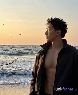 Asian man with short spiky dark brown hair, medium-tan skin from sunset backligh