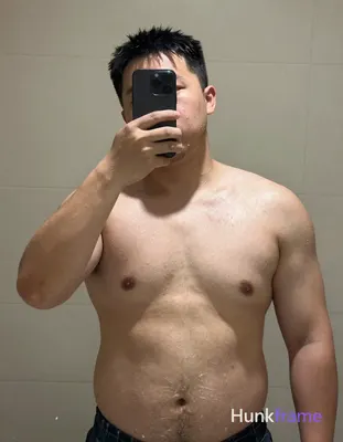 A big hairy stocky masculine man stands shirtless in an indoor bathroom or showe