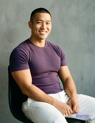 Asian man with short buzz cut and clean-shaven face smiling, seated upright on a