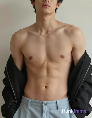 A shirtless man standing with his head slightly tilted forward, wearing a black 