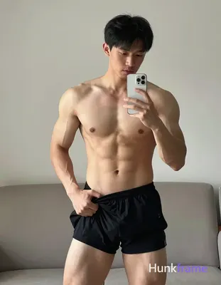 Asian adult man with light to medium tan skin and short straight black hair stands before a mirror i
