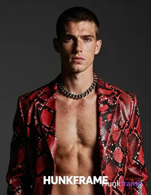 A fair-skinned white man with freckles and short dark cropped hair stands shirtless in a head-and-sh
