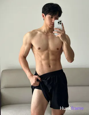 Asian adult man with light to medium tan skin and short straight black hair stands before a mirror i