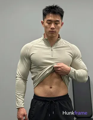 Asian man with light-medium skin and short black textured hair stands facing a mirror, eyes closed i