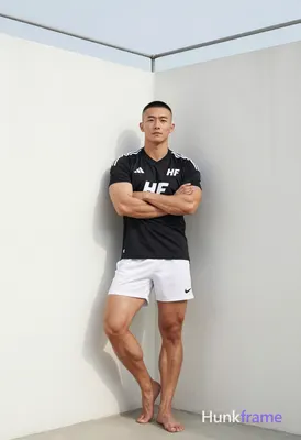 Asian man with short black buzz cut and clean-shaven face, standing leaning agai