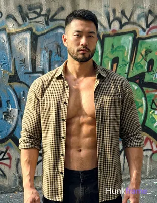 a muscular man standing confidently with his arms slightly bent at his sides, short dark hair and a