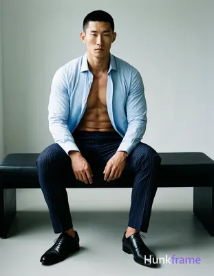 Asian man with short black buzz cut and clean-shaven face, seated upright on a modern black bench in