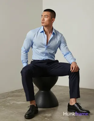 Asian man with short buzz cut and slight upper lip stubble seated on a black scu