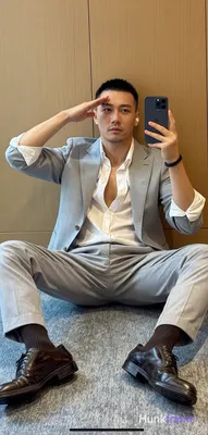 Asian adult man with short black buzz cut and light stubble, neutral expression saluting his forehea