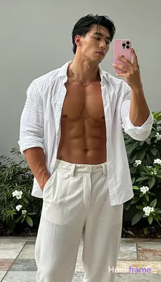 Asian man medium-dark tan skin taking a vertical mirror selfie, standing upright with torso angled l