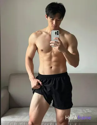 Asian adult man with light to medium tan skin and short straight black hair stands before a mirror i