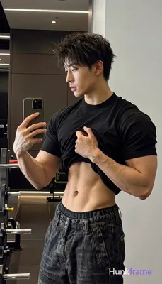Asian adult man with short dark tousled hair and slight chin stubble stands in p