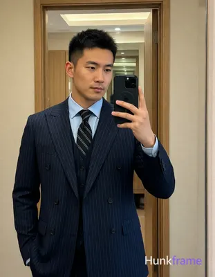 Asian man with short textured dark crop hair and clean-shaven face stands uprigh