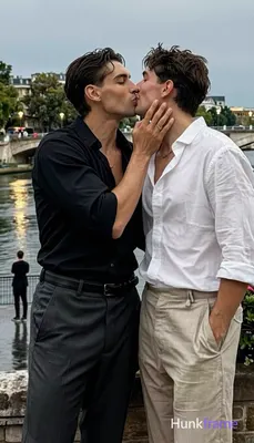 Man on the left has medium-dark skin, short dark wavy side-parted hair, clean-sh