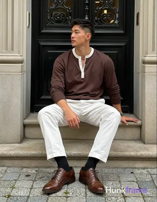 Asian man with short dark brown undercut hair and clean-shaven face He sits on a