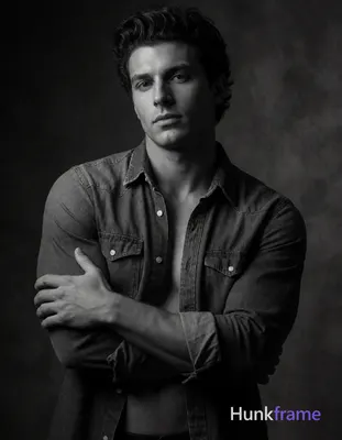 A confident shirtless Caucasian man with a dark thick pompadour and clean-shaven