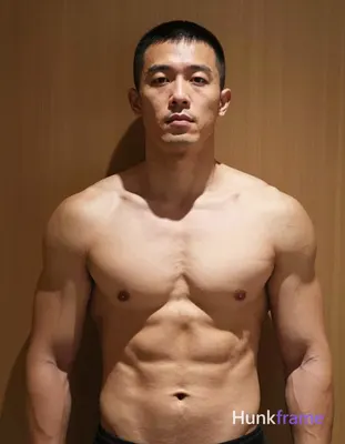 Asian man with short buzz cut and clean-shaven face stands upright facing forwar