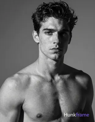 Caucasian man with short dark tousled hair, clean-shaven face, direct gaze and neutral mouth. Shirtl