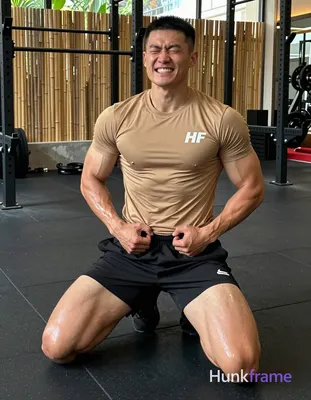 Asian man kneeling on black rubber gym floor, torso upright and slightly arched back with hands clas