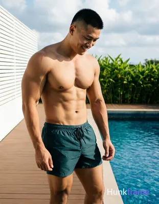 Asian man with short black buzz cut and high temples stands shirtless beside a swimming pool on a wo