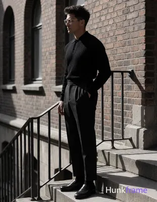 Adult man in profile facing left, standing on stone steps beside a railing with weathered brick faca