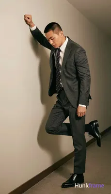 Asian man with short buzz cut and clean-shaven face in a dark gray tailored suit