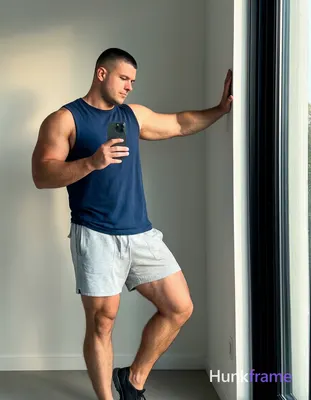 an anonymous figure man with short black buzz cut and clean-shaven face, standing sideways in a 
