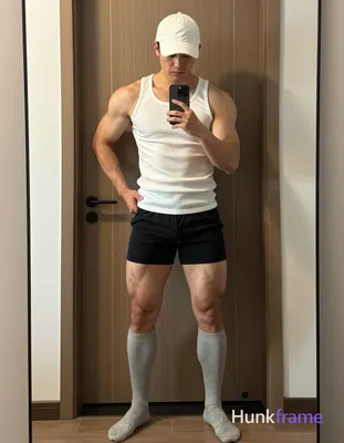 A confident adult man with short dark hair under a white cap stands in a wide st