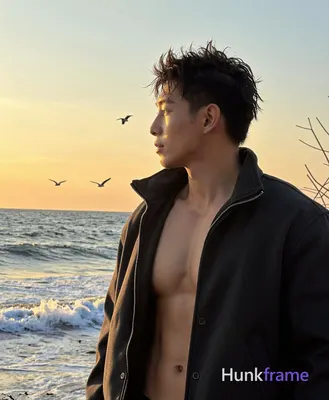Asian man with short spiky dark brown hair, medium-tan skin from sunset backligh