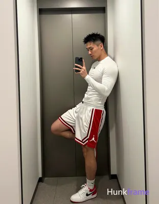 Asian man with short spiky black hair and high fade standing in a modern apartment hallway instead o