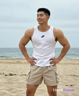 Asian man with short black buzz cut and clean-shaven face, smiling confidently while looking slightl