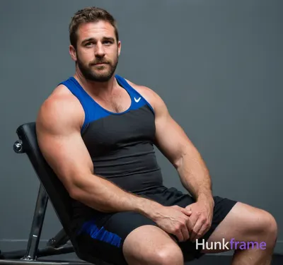 A big hairy stocky masculine man seated on gym equipment, mid-torso to upper thi