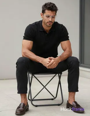 A rugged medium-dark skinned man with short textured dark hair and clear-framed 