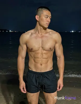 Asian man with short buzz cut and clean-shaven face stands upright in night beac