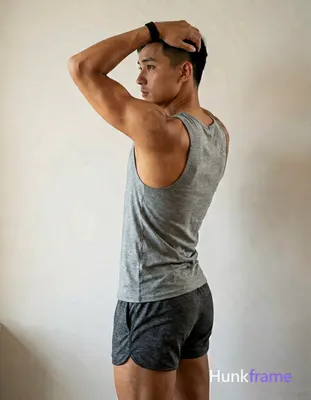 A handsome masculine man as a Xiaohongshu fitness influencer, standing in profile with left arm rais