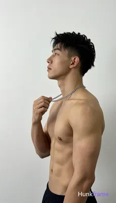 Asian man with short textured black hair and tapered fade stands in profile facing left, shirtless h