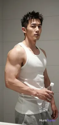 Asian man with short dark textured spiky hair and clean-shaven face stands upright torso angled righ