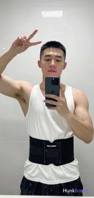 Asian man with short black buzz cut and clean-shaven face, standing facing a bat