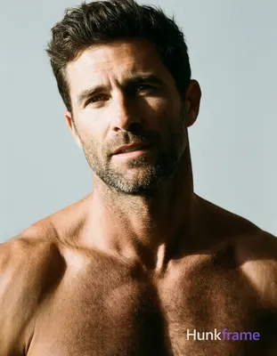 A handsome adult man with light to medium skin, dark brown short textured hair styled upward, and sh